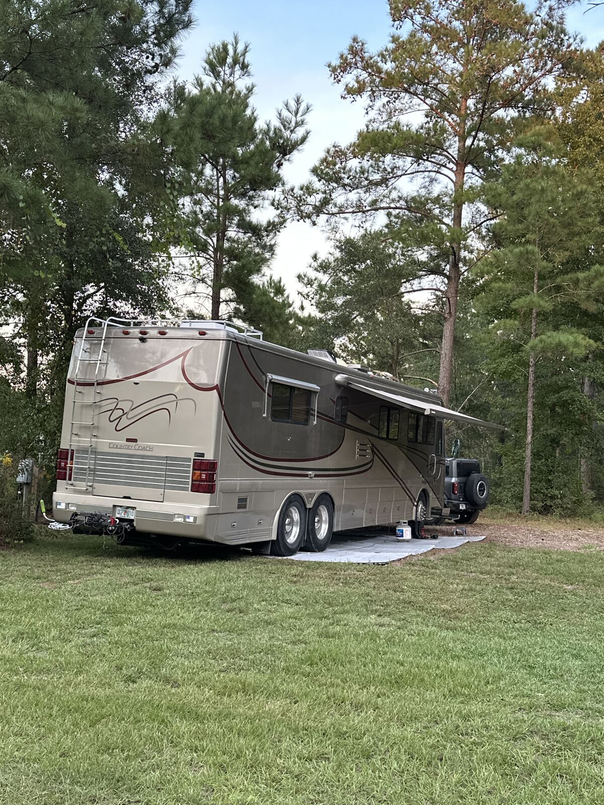 Large Class A motorcoach parked under the pines at the Pine and Power site